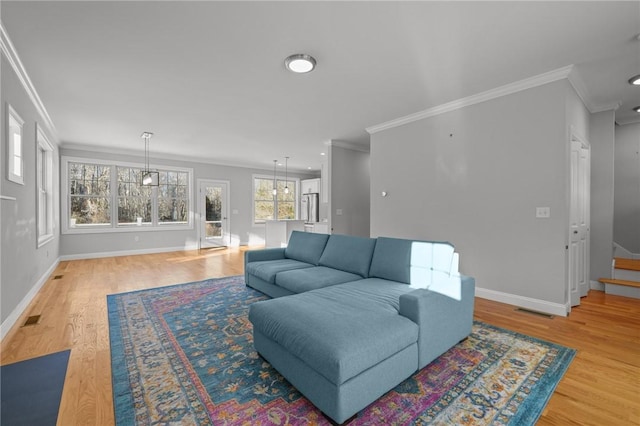 living room with a wealth of natural light, light wood-style flooring, and crown molding