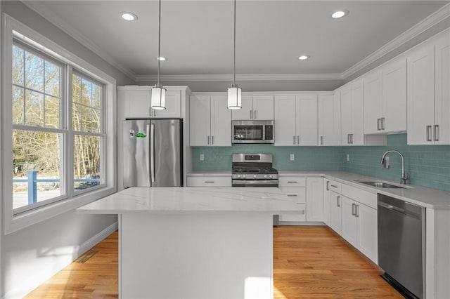 kitchen featuring stainless steel appliances, a center island, decorative light fixtures, and a sink