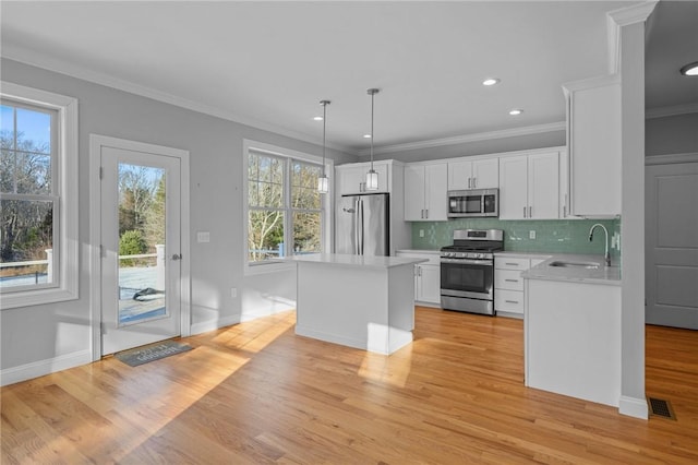 kitchen featuring white cabinets, light countertops, appliances with stainless steel finishes, hanging light fixtures, and a center island