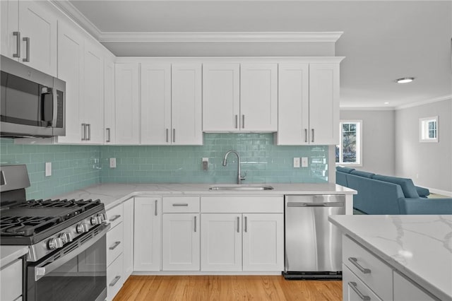 kitchen with crown molding, appliances with stainless steel finishes, a sink, and white cabinets