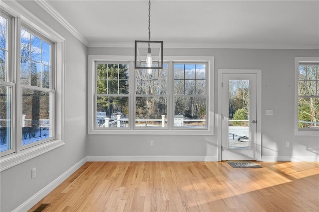 unfurnished dining area with light wood-type flooring, visible vents, baseboards, and crown molding