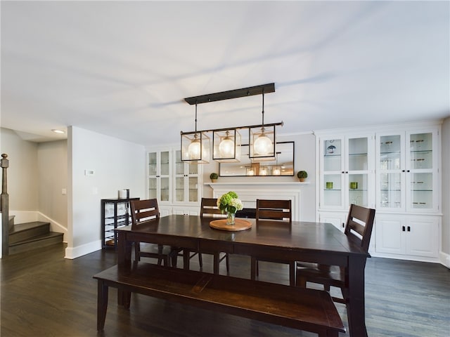 dining area with dark wood-style floors, built in shelves, baseboards, and stairs