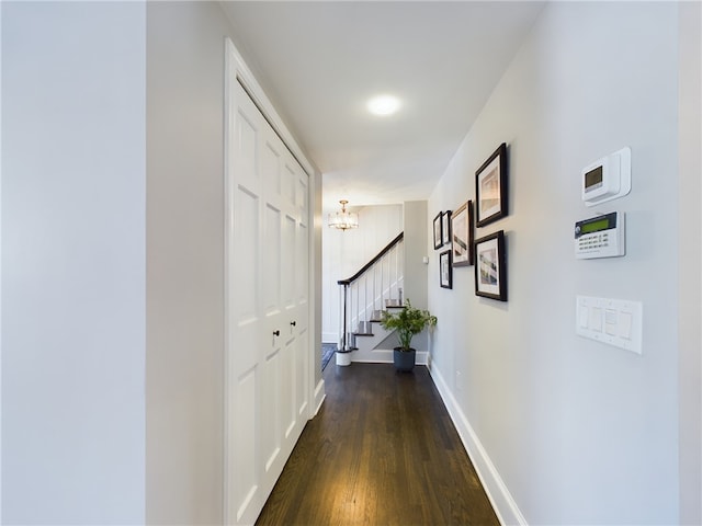 hall with dark wood-style flooring, stairway, baseboards, and an inviting chandelier