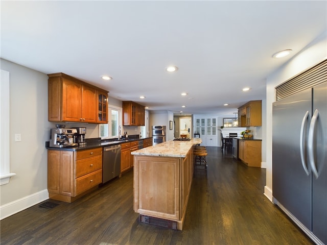 kitchen featuring recessed lighting, baseboards, appliances with stainless steel finishes, a center island, and dark wood finished floors