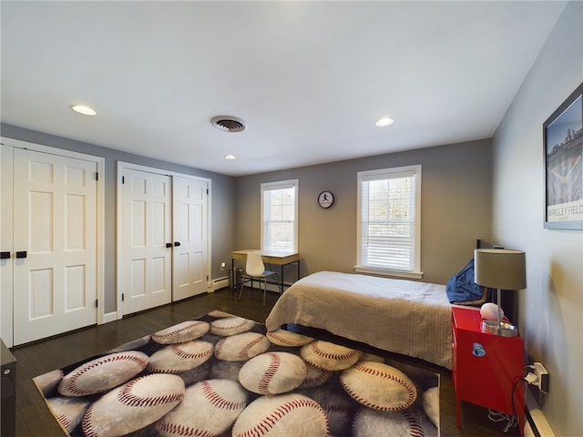 bedroom with visible vents, wood finished floors, baseboard heating, multiple closets, and recessed lighting