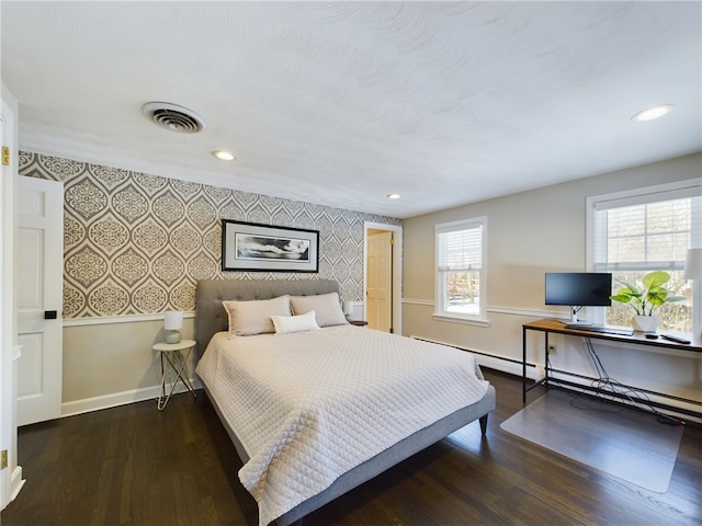 bedroom featuring an accent wall, wood finished floors, visible vents, and wallpapered walls