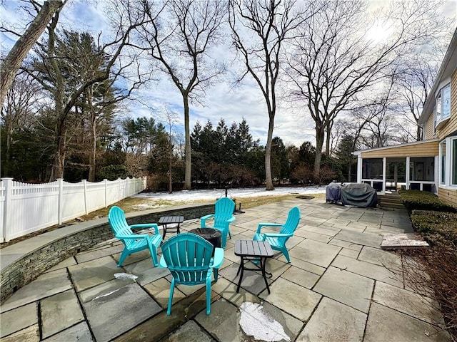 view of patio with a sunroom, a fenced backyard, a grill, and a fire pit