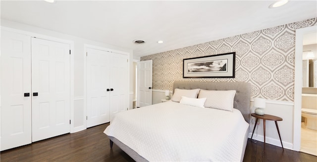 bedroom with wallpapered walls, baseboards, visible vents, wood finished floors, and multiple closets