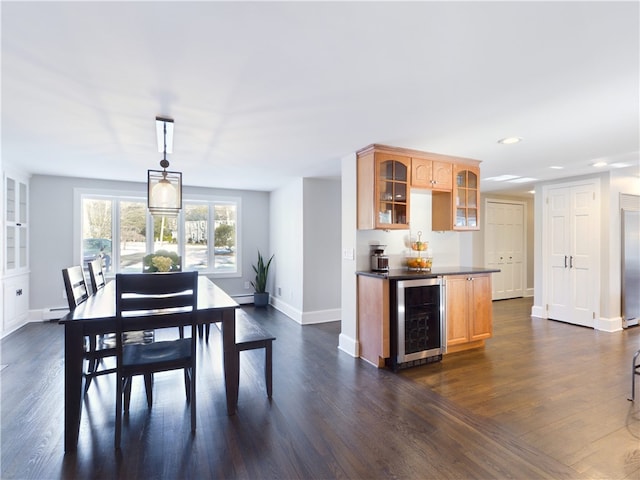 dining room featuring wine cooler, dark wood-style flooring, a dry bar, baseboard heating, and baseboards