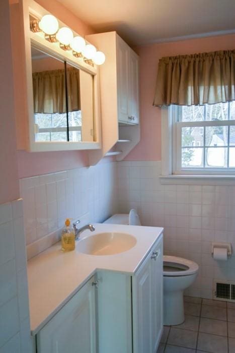 bathroom featuring visible vents, toilet, tile patterned flooring, vanity, and tile walls