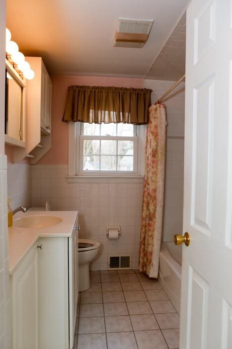 full bathroom featuring visible vents, toilet, tile patterned floors, vanity, and tile walls