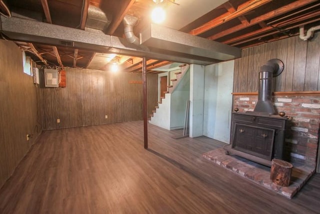 finished basement with electric panel, wooden walls, stairway, and wood finished floors