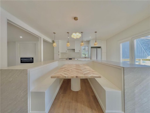 kitchen with pendant lighting, white cabinetry, light countertops, and freestanding refrigerator