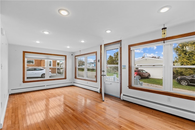 interior space with light wood-type flooring, a baseboard radiator, a wealth of natural light, and recessed lighting