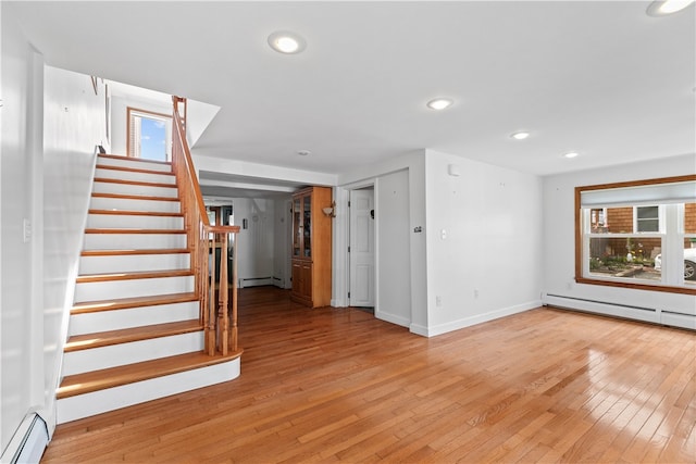 interior space with a baseboard heating unit, recessed lighting, stairs, and light wood-style floors