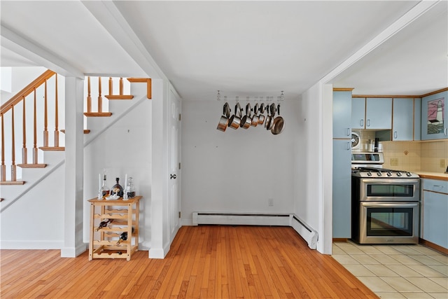 kitchen featuring range with two ovens, light wood-type flooring, light countertops, and backsplash