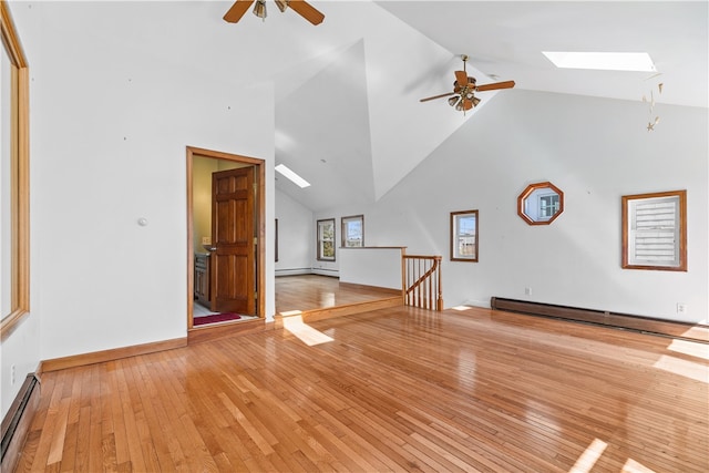 unfurnished living room featuring a skylight, baseboard heating, and light wood-style floors