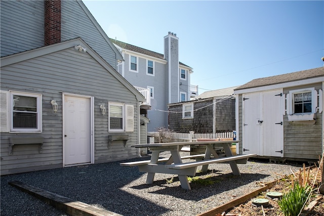 exterior space with a chimney, an outdoor structure, fence, and a shed