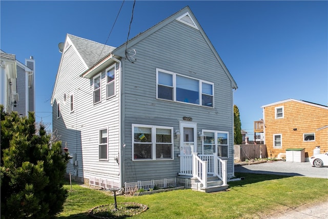 back of property with a lawn and roof with shingles