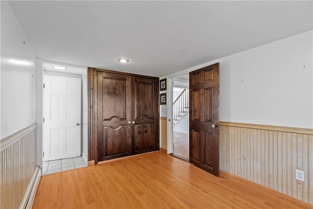 interior space featuring a wainscoted wall, light wood-style flooring, and baseboard heating