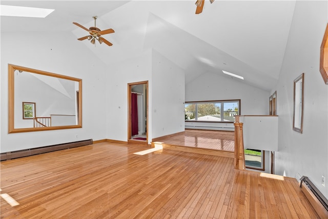 unfurnished living room featuring ceiling fan, high vaulted ceiling, a baseboard heating unit, a skylight, and light wood-style floors