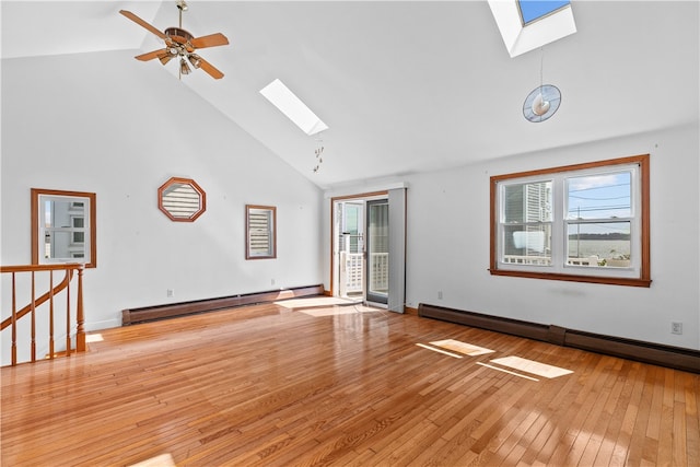 empty room with a baseboard heating unit, a skylight, high vaulted ceiling, and light wood-style flooring