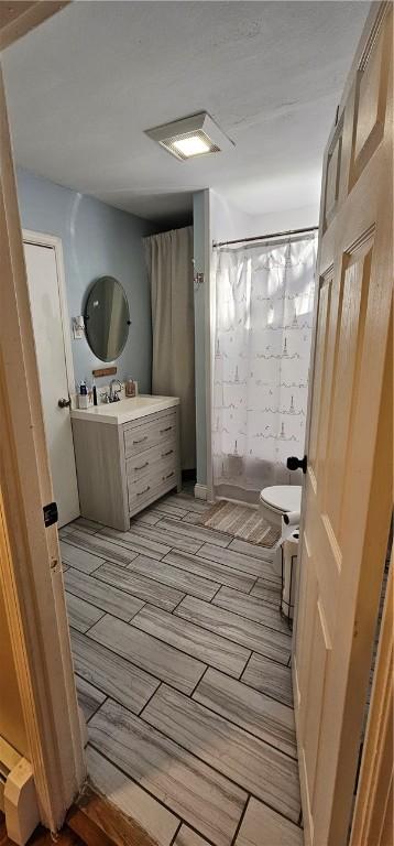 bathroom featuring a shower with shower curtain, toilet, and vanity