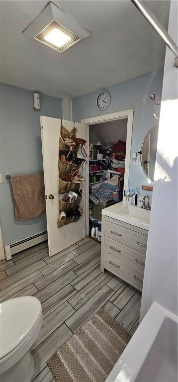 full bathroom with a baseboard heating unit, vanity, and toilet