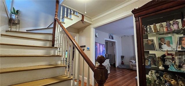 staircase with wood finished floors and crown molding