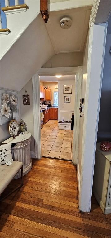 corridor with light wood finished floors and vaulted ceiling