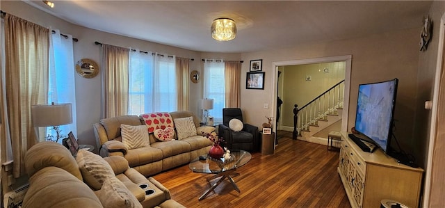 living room with a baseboard heating unit, stairway, and dark wood finished floors