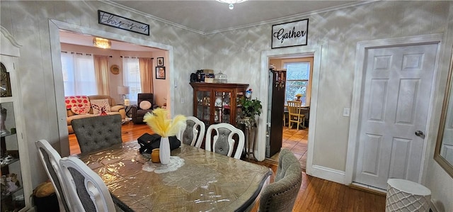 dining space featuring ornamental molding, baseboards, and wood finished floors