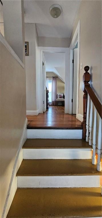 staircase featuring baseboards and wood finished floors