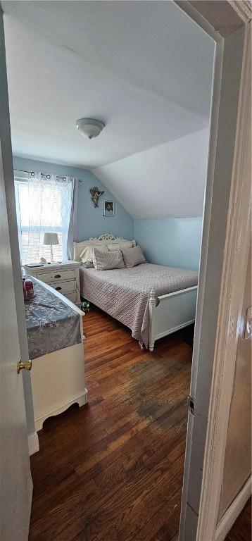 bedroom with vaulted ceiling and dark wood finished floors