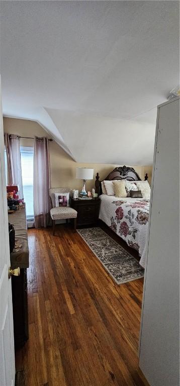 bedroom with dark wood-style floors and vaulted ceiling