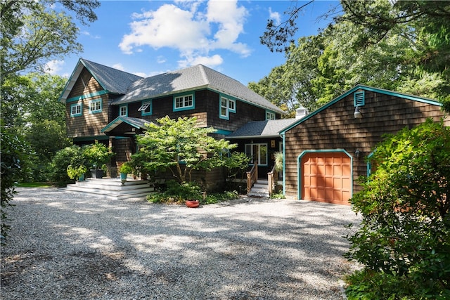 shingle-style home featuring a garage, gravel driveway, and roof with shingles