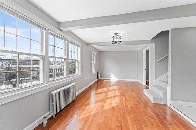 interior space with radiator heating unit, stairs, baseboards, and light wood-style flooring