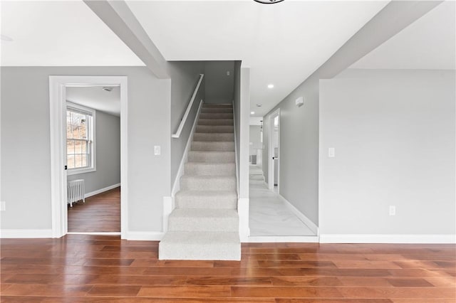 staircase featuring baseboards, recessed lighting, wood finished floors, and radiator