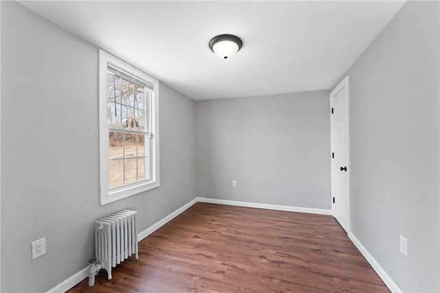 unfurnished room featuring dark wood-style floors, radiator, and baseboards