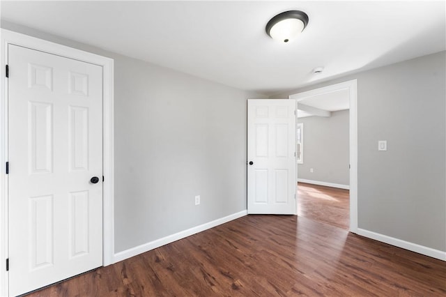 unfurnished room with dark wood-style floors and baseboards