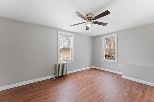 unfurnished room featuring baseboards, plenty of natural light, wood finished floors, and radiator