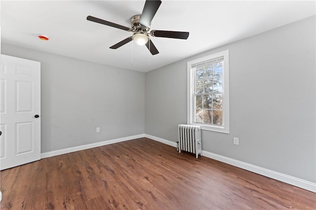 unfurnished room featuring dark wood-style floors, baseboards, radiator heating unit, and a ceiling fan