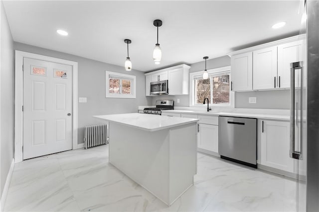 kitchen featuring appliances with stainless steel finishes, radiator, light countertops, and white cabinets