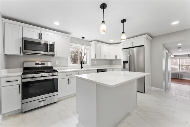 kitchen with radiator heating unit, hanging light fixtures, stainless steel appliances, light countertops, and a sink