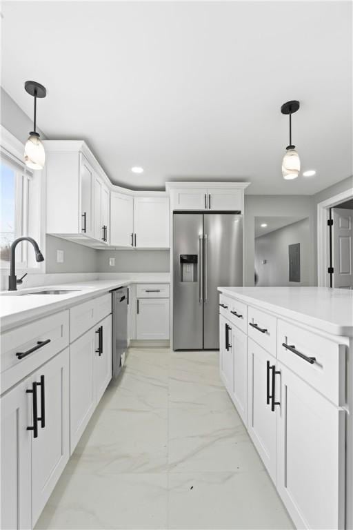 kitchen with a sink, white cabinetry, light countertops, appliances with stainless steel finishes, and pendant lighting