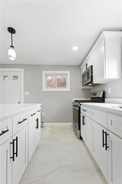 kitchen featuring white cabinetry, appliances with stainless steel finishes, light countertops, and decorative light fixtures