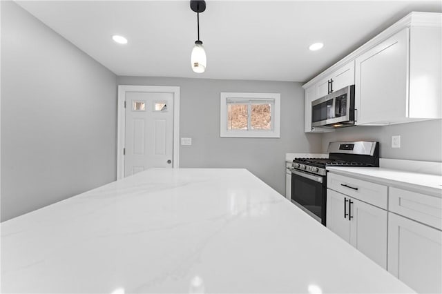 kitchen featuring recessed lighting, stainless steel appliances, white cabinetry, hanging light fixtures, and light stone countertops