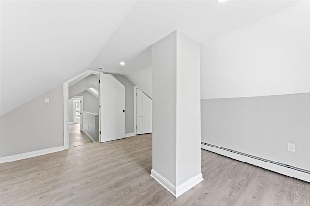 additional living space featuring baseboards, vaulted ceiling, light wood finished floors, and baseboard heating