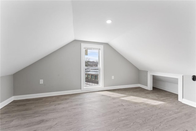 bonus room with lofted ceiling, baseboards, and wood finished floors