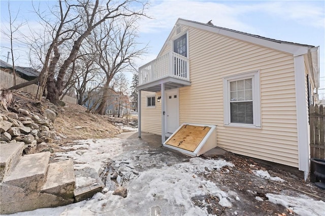 snow covered house featuring a balcony